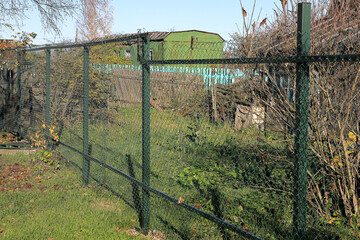 Fence made of steel mesh with a polymer coating near an abandoned cottage