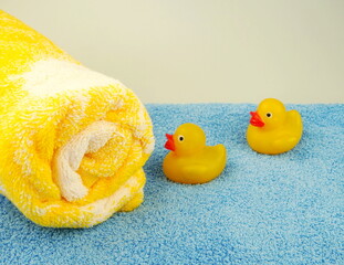 Soft terry blue and yellow towels with a ducklings for a holiday at sea. Items for cleanliness, hygiene in  bath and shower. Space for text.	