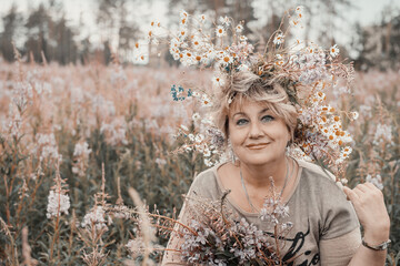 Beautiful woman 60 years old in nature wearing a wreath of flowers in her hair. Great looking...