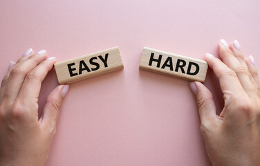 Easy or Hard symbol. Concept word Easy or Hard on wooden blocks. Businessman hand. Beautiful pink background. Business and Easy or Hard concept. Copy space