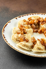 vareniki with potato filling and fried onions, Ukrainian cuisine on a dark background. vertical image. top view. copy space for text