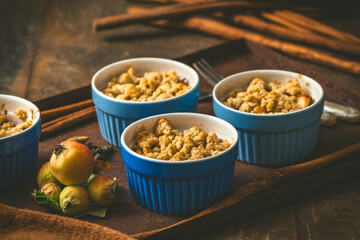 Apple crumble in small molds on dark wood