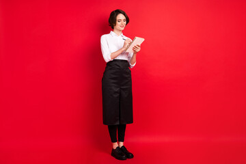 Full length photo of happy nice young woman hold note write order good mood isolated on rec color background