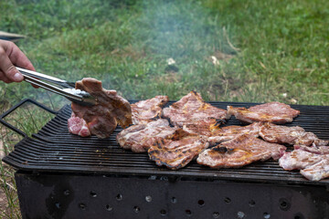 Man cooking meat on barbecue grill at bbq party in summer garden. Food, people and family time concept.