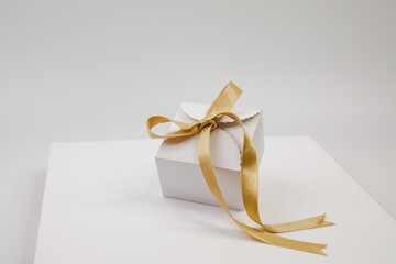 Golden ribbon with a bow on a rectangular box, illuminated by soft lighting