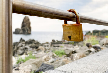Rusty padlock with a heart design on a metal railing