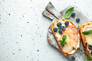 Delicious toast with cream cheese, honey, peaches and blueberries. Concept healthy and balanced...