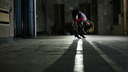 Brunette girl dressed in Halloween style. Female gymnast, creepy scene. Depression, suffering, crime. Black Carnival, in the basement. The girl dancer poses in front of the camera