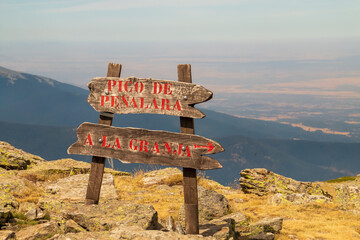 Cartel de madera direccional en el sendero, hacia el pico de Peñalara o La Granja en Segovia, Sierra de Guadarrama, Madrid, España. - obrazy, fototapety, plakaty