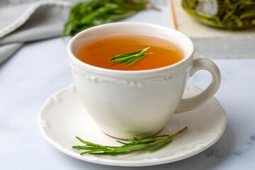 Cup of healthy rosemary tea with fresh rosemary bunch on rustic background, winter herbal hot drink concept, salvia rosmarinus