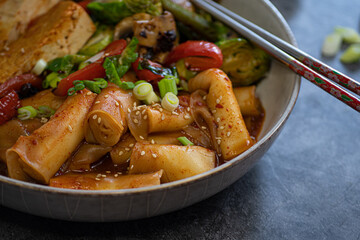 Tteokbokki- korean rice cakes and vegetable stew served in white bowl, traditional steel chopsticks.