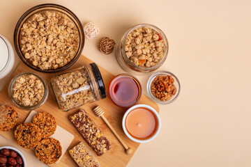 Crispy granola in a bowl, granola bars, honey and glass of milk, hazelnuts on a wooden desk from...