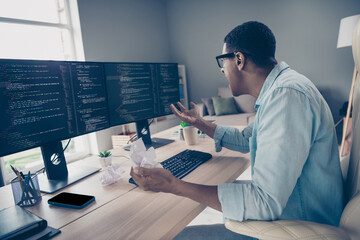 Side photo of young system administrator man stressed scream at his computer cant fix program issue he crumpled papers office indoors - obrazy, fototapety, plakaty