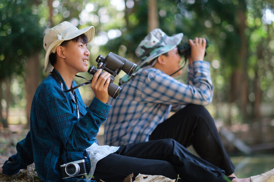 Two young boys exploring the forest hiking and camping, learning about the wildlife, using binoculars to search for animals with friends. Happy smiling excited summer vacation. - Powered by Adobe