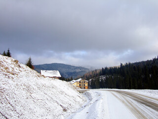 A dirt winter road descends to a ski resort with hotels under the mountain