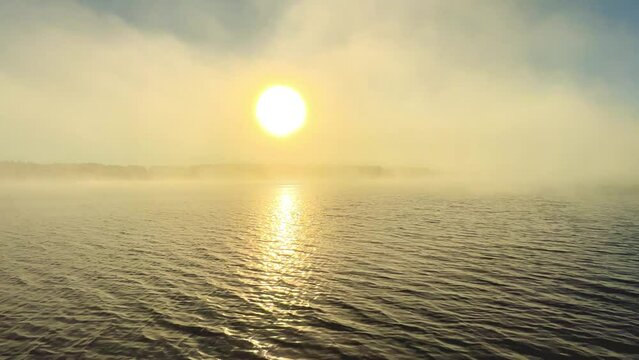 Dawn on the lake in Karelia. A magical landscape on the lake, the evaporation of the river, the sun's rays through the fog over calm water, camera movement, slow motion. The light of the morning dawn.