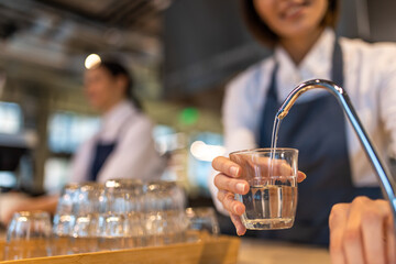 Girl in apron cleaning a cup and looking contented