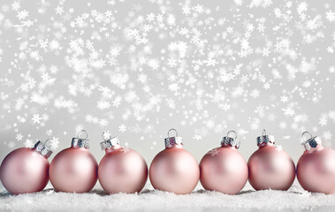Christmas card. Pink baubles and snowflakes with snowfall.