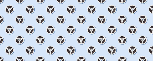 Seamless pattern of white reels for tape recorder isolated on blue background.