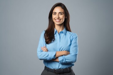 Happy young smiling confident professional business woman wearing blue shirt, pretty stylish female executive looking at camera, standing arms crossed isolated on gray background