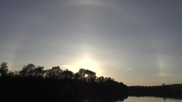 Unusual atmospheric phenomena. Very bright double halo (parhelic ring) over river at moment of evening sunset, windless spring day. Average flow of Don River. Mock sun with reflection in water