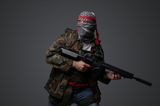 Militant from the Middle East, dressed in a white keffiyeh and camouflaged field attire, wielding an automatic rifle, set against a neutral gray backdrop