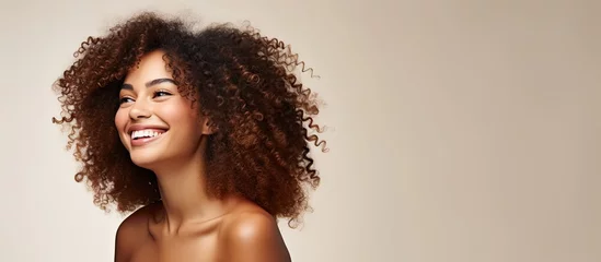 Tuinposter The African woman with her beautiful curls stands against an isolated background in a fashionable spa showcasing her girl s natural beauty and radiant smile on her happy face in a captivati © TheWaterMeloonProjec