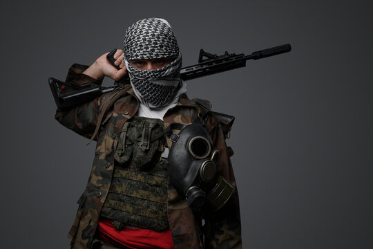 Middle Eastern radical fanatic soldier donning a white keffiyeh and camouflaged field uniform, armed with an automatic rifle, against a gray background - Powered by Adobe