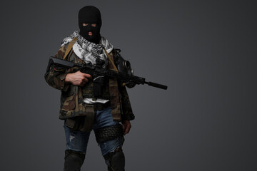 A Middle Eastern radical soldier dressed in a black balaclava and camouflaged field uniform, armed...