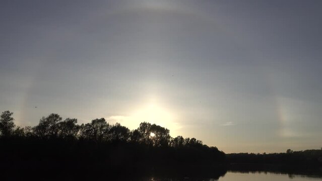 Unusual atmospheric phenomena. Very bright double halo (parhelic ring) over river at moment of evening sunset, windless spring day. Average flow of Don River. Mock sun with reflection in water