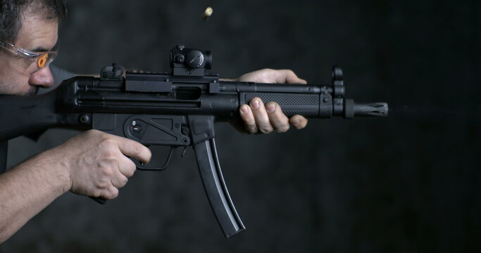 Firing weapon in high-speed, HK SP5K GUN side view. Person aiming and shooting German assault rifle