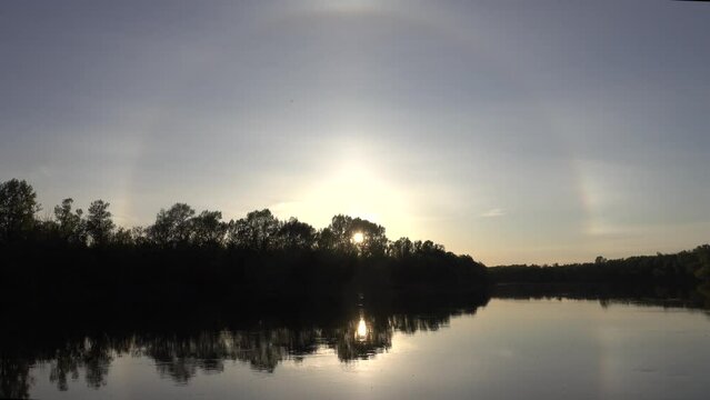 Unusual atmospheric phenomena. Very bright double halo (parhelic ring) over river at moment of evening sunset, windless spring day. Average flow of Don River. Mock sun with reflection in water