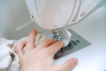 A woman seamstress sews things from fabric on a CNC sewing machine.