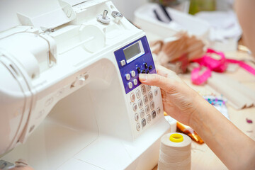 A woman seamstress sets up a program on a CNC sewing machine.