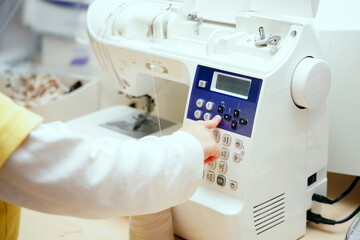 A little girl presses buttons on a cnc sewing machine.