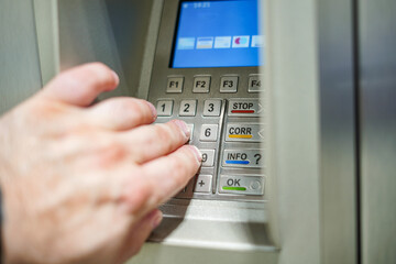 A man enters a PIN code at an ATM to withdraw cash.
