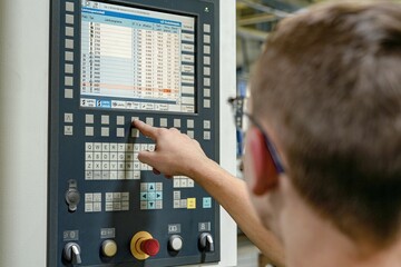 A worker writes a program on a CNC milling and lathe machine. Checking and correcting errors in CNC...