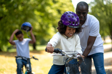 Happy dad teaching his kids to ride a bike