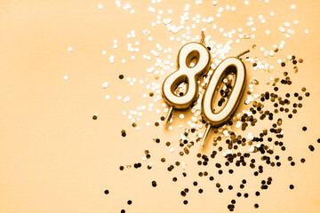 80 years celebration festive background made with golden candles in the form of number Eighty lying on sparkles. Universal holiday banner with copy space.