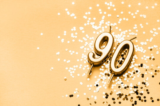 90 years celebration festive background made with golden candles in the form of number Ninety lying on sparkles. Universal holiday banner with copy space.