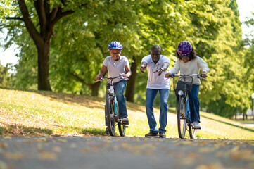 Obraz premium Cute family riding bikes in a park