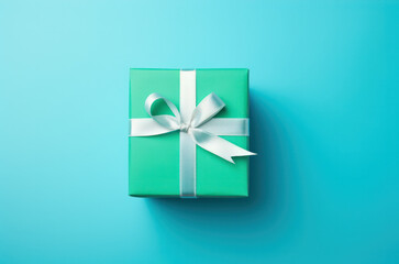 Green gift box with white ribbon on clean blue background. Christmas gift. Top view.