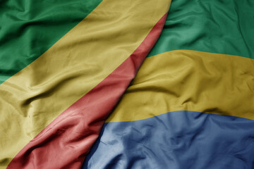 big waving national colorful flag of republic of the congo and national flag of gabon .