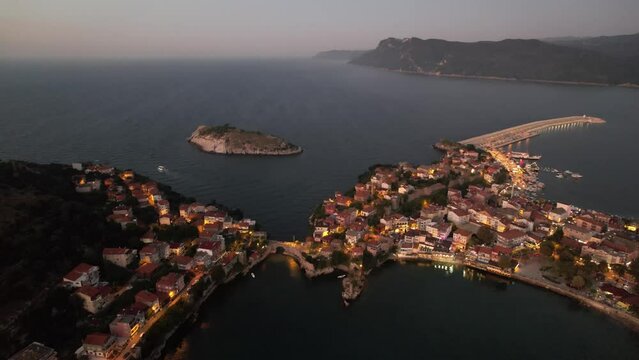 City view in the Amasra mountains. The drone is slowly approaching the beautiful landscape. Aerial view of houses and deep blue sea. Amasra, Turkey.