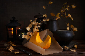 Still life with pumpkin slice, autumn branches and black pots in vintage style.