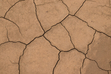 Dry soil background, cracked bare earth texture. Top view. Drought, global warming, climate change concept.