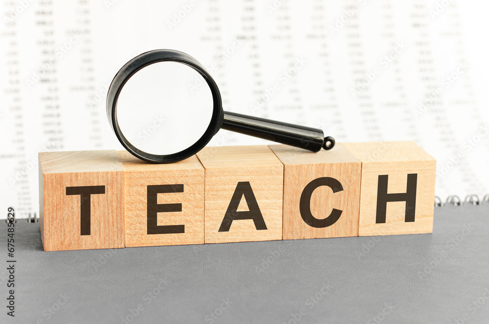 Poster on wooden blocks under a magnifying glass text: teach. teach - words from wooden blocks with letters