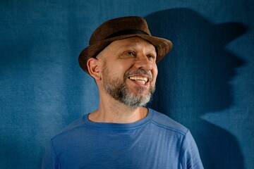 a man wearing a hat smiles while standing in front of a dark blue wall