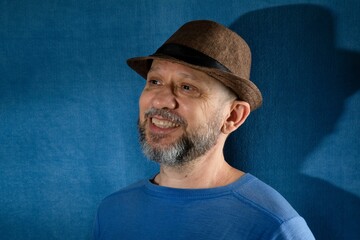 Mature Caucasian male wearing a brown fedora hat smiling and posing for the camera