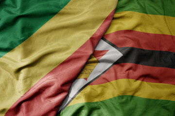 big waving national colorful flag of republic of the congo and national flag of zimbabwe .